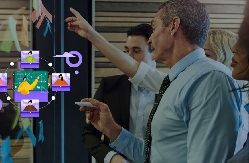 A group of executives stand at a clear writing board sharing their thoughts, the men are in front.